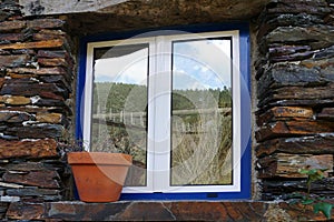 Blue window with blue trim and a rustic stone wall