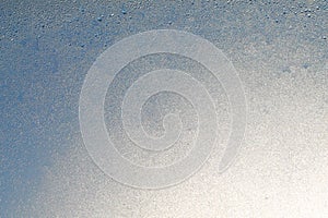 Blue window glass covered hoarfrost ice pattern texture. Cold nature winter background photo