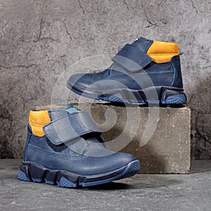 Blue winter sports shoes with orange inserts and velcro for men on a gray concrete background.