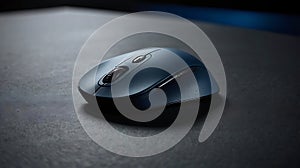 A blue wireless computer mouse on a dark surface in a close up shot