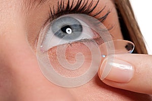 Blue woman eye with contact lens applying