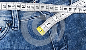 A blue woman jeans and ruler, concept of diet and weight loss. Jeans with measuring tape. Healthy lifestyle, dieting, fitness.