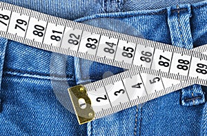 A blue woman jeans and ruler, concept of diet and weight loss. Jeans with measuring tape. Healthy lifestyle, dieting, fitness.