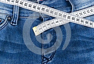 A blue woman jeans and ruler, concept of diet and weight loss. Jeans with measuring tape. Healthy lifestyle, dieting, fitness.