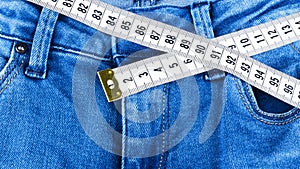 A blue woman jeans and ruler, concept of diet and weight loss. Jeans with measuring tape. Healthy lifestyle, dieting, fitness.