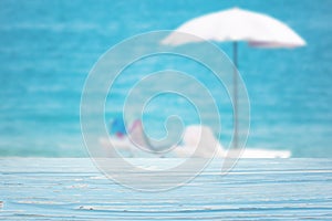 blue wood table top on blur beach umbrella on the sea background