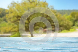 blue wood table top on blur green tree and blue sky background