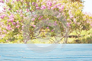 blue wood table top on blur trees with pink flowers background