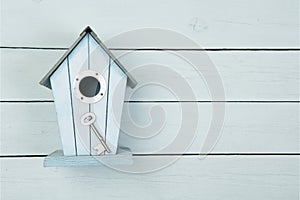 Blue wooden bird house with a metal key on a blue wooden background with copy space as a concept for a new home