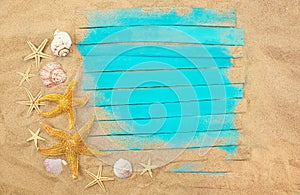 Blue wooden boards with starfish, shells in sand. Summer frame. Concept of vacation, sea, travel