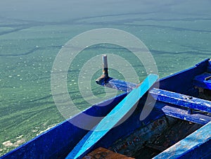 Blue wooden boat detail on  lake green water with algae.  Kastoria, Greece