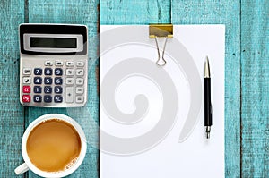 Blue wooden desk table with paper ream, pen, calculator and cup