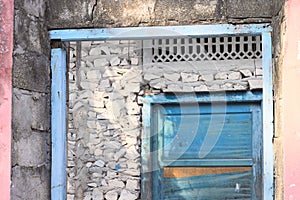 Blue wooden door in a stone wall of an abandoned pink house