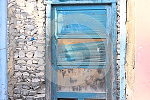 Blue wooden door in a stone wall of an abandoned pink house