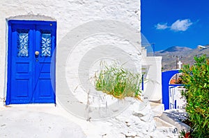 Blue wooden door, white wall and flowers in Greece