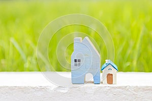 Blue wooden house with niminature hosue over blurred natural green garden background