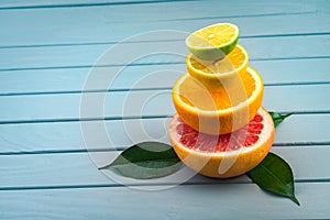 On a blue wooden table lies a cut of grapefruit, on top is orange, lemon and lime