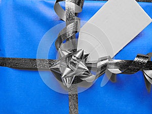 Blue wrapped gift with blank tag and pretty shiny ribbon