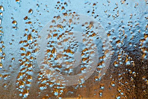 Blue-yellow background of wet glass with raindrops, splashes