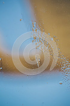 Blue-yellow background of wet glass with raindrops, splashes and