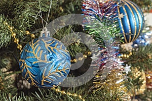 Blue-yellow ball among the needles, a festive decoration of the New Year tree