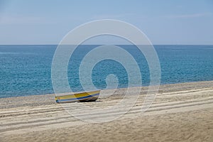 Blue and Yellow boat in a Mediterranean beach of Ionian Sea - Bova Marina, Calabria, Italy