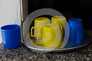 blue and yellow colored plastic cups on top of a metal tray
