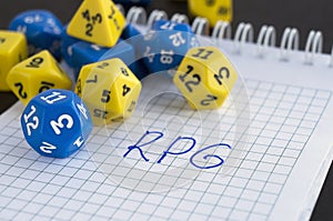 Blue and yellow dices for rpg, dnd, or tabletop games. A notebook with word RPG.