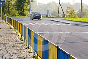 Blue and yellow fence dividing sidewalk from road