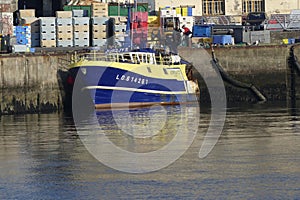 Blue and yellow Fishing boat alongside the wharf.