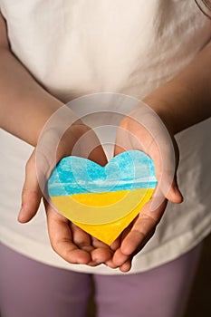 Blue-yellow heart in the hands of a little girl