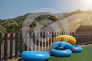 Blue and yellow inflatable wheels against background of wooden fence and nature