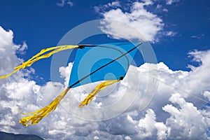 A blue and yellow kite flying against a sky photo