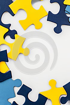 Blue, yellow, navy pieces of puzzle frame on white background. World autism awareness day concept. Top view, copy space