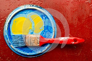 Blue and yellow paint with paint brush over red background