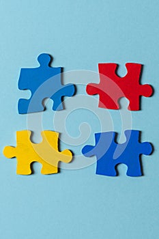 Blue, yellow, red pieces of puzzle on light blue background. World autism awareness day concept. Top view, copy space