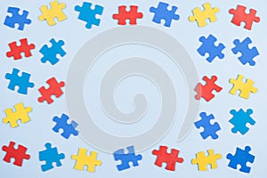Blue, yellow, red pieces of puzzle on light blue frame background. World autism awareness day concept. Top view, copy