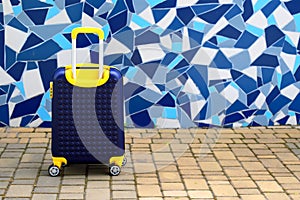 Blue yellow travel suitcase on background of vintage mosaic wall. Vacation, weekend, travel, tourism. Suitcase ,hotel, guest house