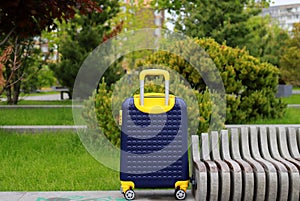 Blue yellow travel suitcase on wheels near bus station, airport, travel. Beautiful Suitcase near hotel, hostel, guesthouse, home