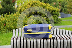 Blue yellow travel suitcase on wheels near bus station, airport, travel. Beautiful Suitcase near hotel, hostel, guesthouse, home