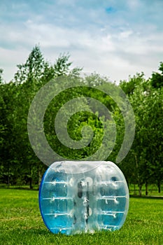 Blue Zorbing Balloon on the summer lawn. inflatable zorb ball outdoor. Leisure activity concept with vertical copy space