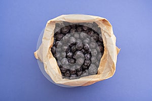 Blueberries background. Ripe and juicy blueberries in paper bag over blue background, . Copy space