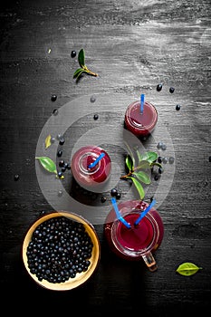 Blueberries and blueberry juice. On black wooden background.