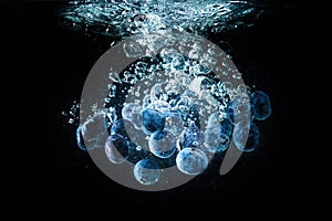 Blueberries falling into a water isolated on black background