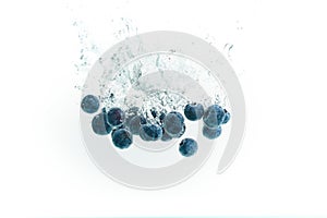 Blueberries falling into water on white background