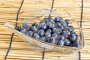 Blueberries in the glass bowl on the wooden background with blueberries