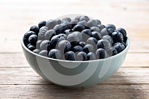 Blueberries in green bowl on wood