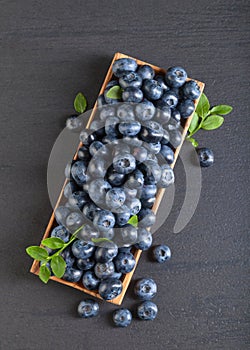 Blueberries with green leaves in old wooden dish