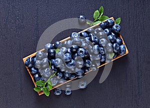 Blueberries with green leaves in wooden dish