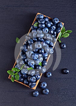 Blueberries with green leaves in wooden dish